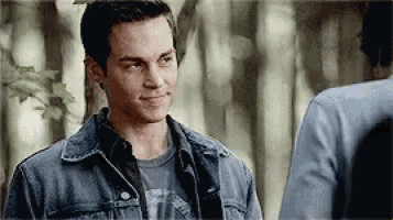 a man in a denim jacket is standing next to another man and smiling .