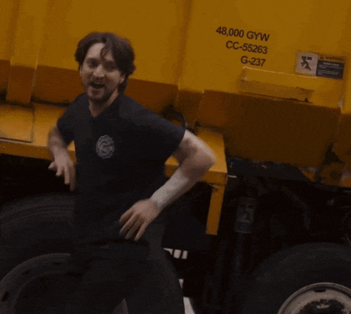 a man is standing in front of a yellow dumpster that says 48,000 gyw cc-55263 g-237
