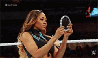 a woman is looking at herself in a mirror during a wrestling match