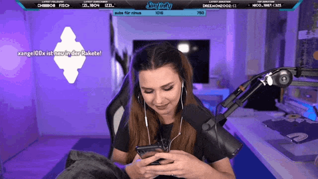 a woman sitting in front of a microphone looking at her phone with a banner that says king freddy