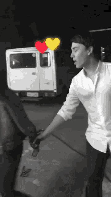 a man in a white shirt holds a woman 's hand in front of a white van