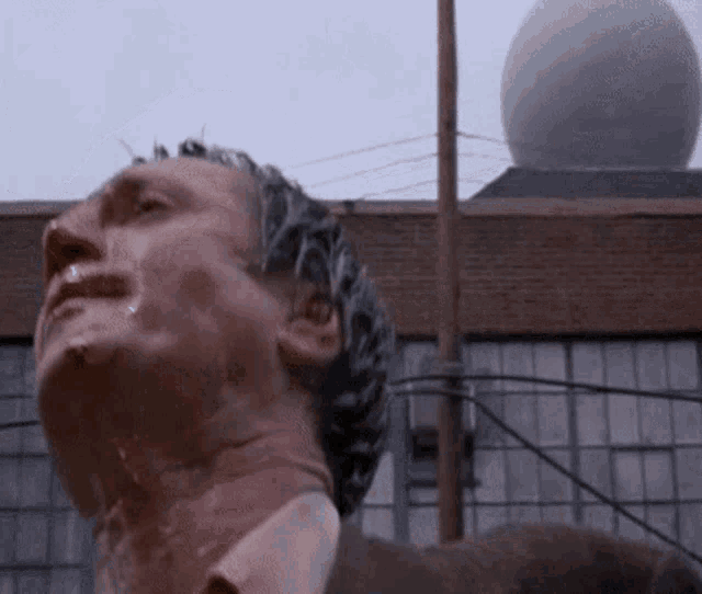 a man is standing in front of a building with his head covered in soap and water .