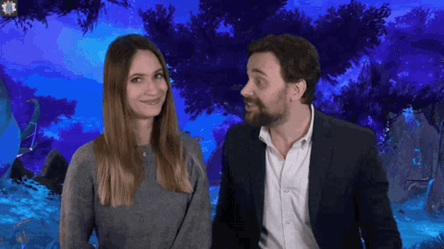 a man in a suit and a woman in a sweater are standing next to each other