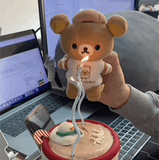 a person is holding a teddy bear with a candle in its mouth
