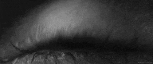 a black and white photo of a person 's eye with a blurred background .