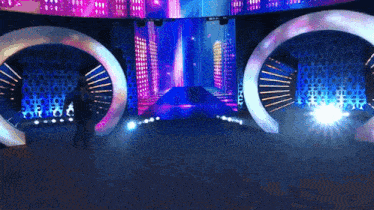 a man stands in front of a stage with a large screen behind him that says ' city '