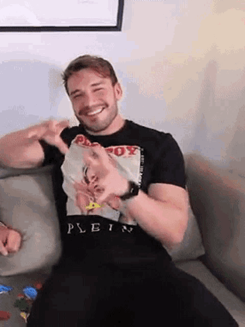 a man is sitting on a couch wearing a playboy t-shirt