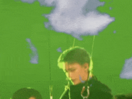 a man is standing in front of a green screen with a cloud in the sky .