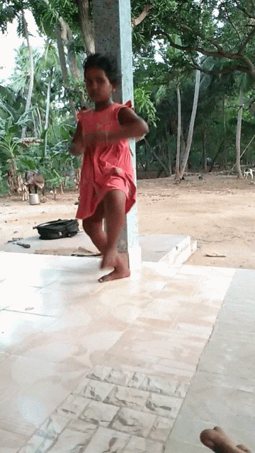 a little girl in a pink dress is standing on a tile floor