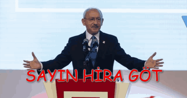 a man in a suit and tie stands at a podium with the words sayin hira got written above him