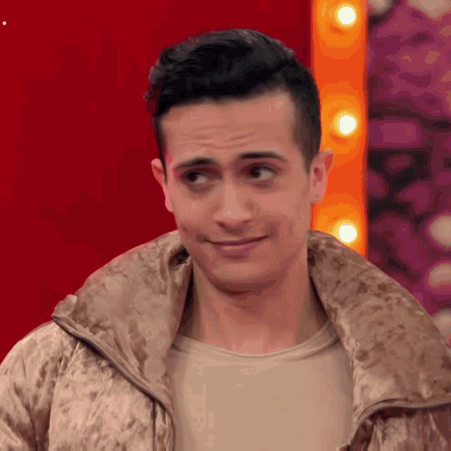 a man in a brown jacket is making a funny face while standing in front of a red background .