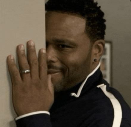 a man with a ring on his finger is peeking over a wall