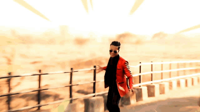 a man in a red jacket and black pants is walking along a railing