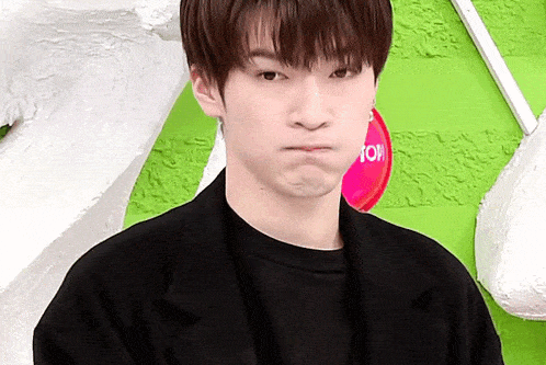 a young man is making a funny face while standing in front of a green and white wall .