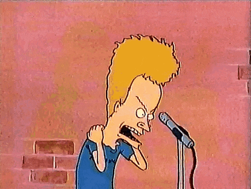 a cartoon character from beavis and butthead is standing in front of a microphone with his arms in the air .