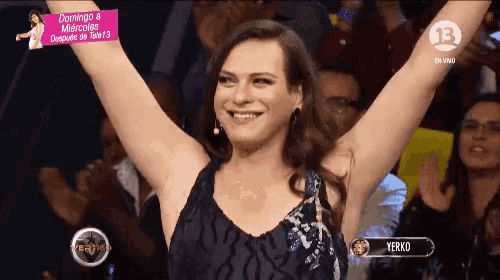 a woman stands in front of a crowd with her arms in the air and the number 13 on the bottom right