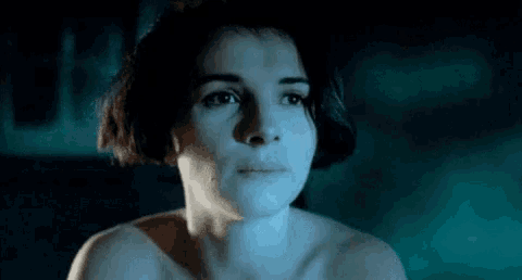 a close up of a woman 's face in a dark room with a blue light shining on her face .