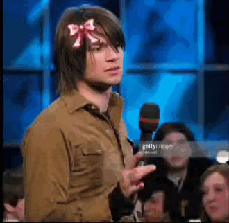 a man wearing a bow on his head is talking into a microphone