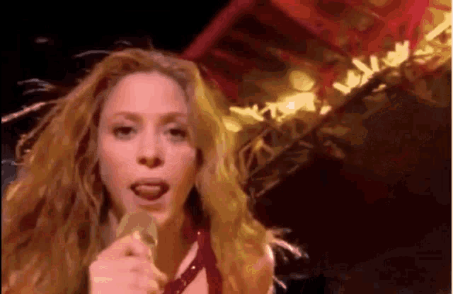a woman with long blonde hair is singing into a microphone