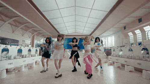 a group of young women are dancing in a bathroom with a sign that says ' nct ' on it