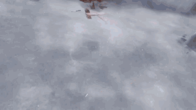 a woman in a video game is sitting on a snowy hill with a sword in her hand .