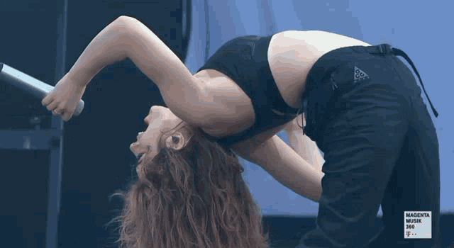 a woman is doing a yoga pose in front of a magenta music 360 advertisement