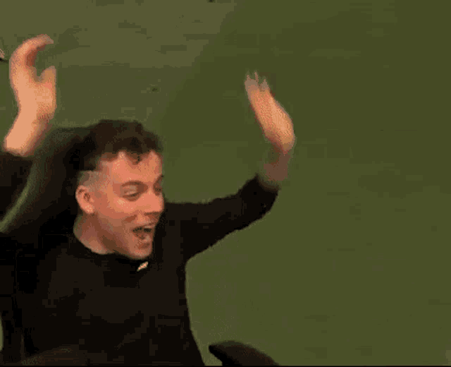 a man is sitting on a couch with his arms in the air .