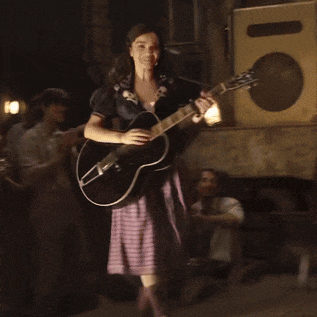 a woman in a plaid skirt plays a guitar