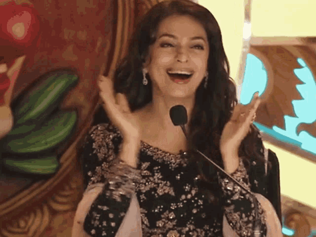 a woman sitting in front of a microphone laughing and clapping her hands