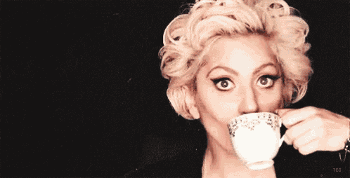 a woman is drinking a cup of tea from a saucer .
