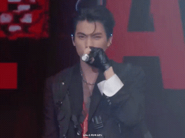 a man in a black jacket is holding a microphone in his hand .