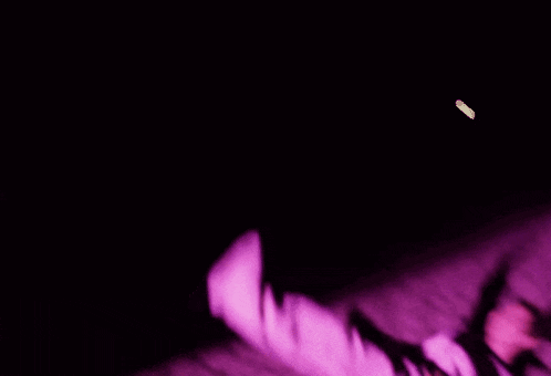 a blurry picture of a person laying on their stomach on a beach at night .
