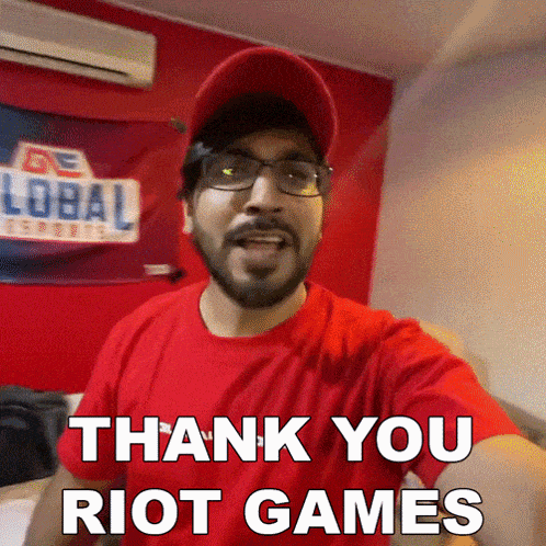 a man wearing glasses and a red hat is saying thank you riot games
