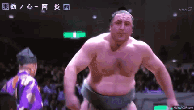 a sumo wrestler is standing in front of a crowd with the letters nhk on the bottom right
