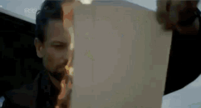 a man is lighting a cigarette and looking at a piece of paper