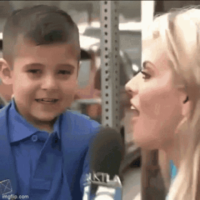 a woman is talking into a microphone while a young boy looks on .