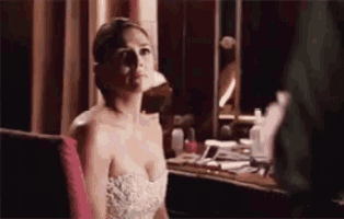 a woman in a strapless white dress is sitting in front of a mirror .