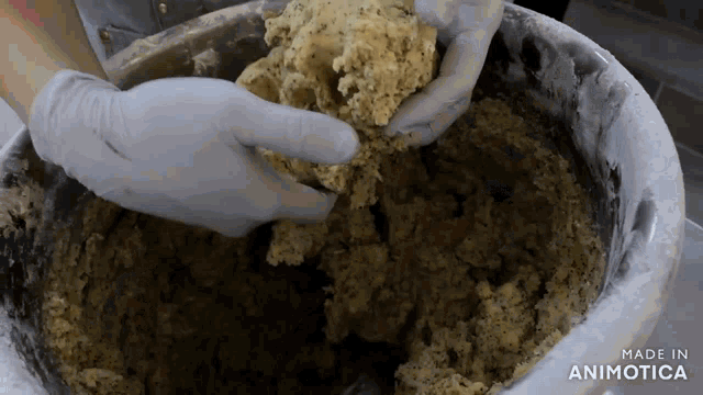 a person is mixing a dough in a bowl with the words made in animatica on the bottom