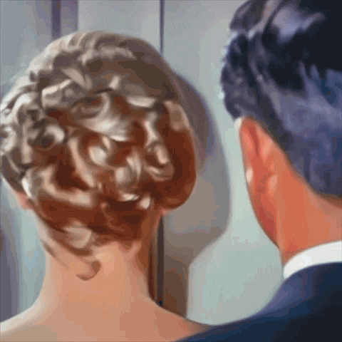 a man and a woman are looking at each other with the woman 's hair in a bun