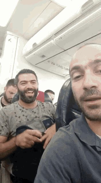 a group of men are sitting on an airplane and one of them is wearing a shirt that says triangles