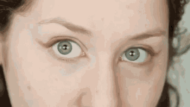 a close up of a woman 's green eyes with a slight smirk on her face .