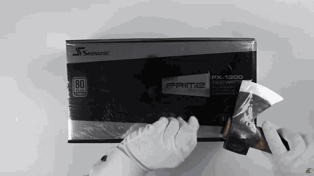 a person wearing white gloves is opening a seasonic px-1300 prime power supply