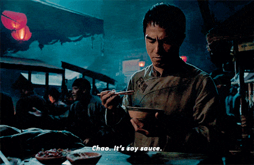 a man is holding a bowl of food with chopsticks and says  chao it 's soy sauce