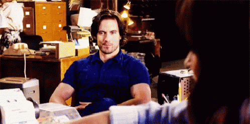 a man in a blue shirt is sitting at a desk with a woman .