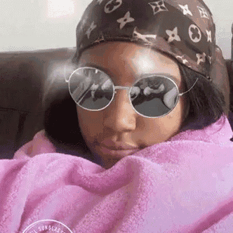a woman wearing sunglasses and a bandana is sitting on a couch .