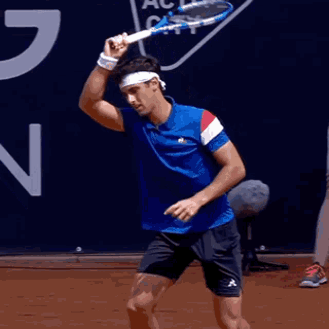 a man in a blue shirt is holding a tennis racquet