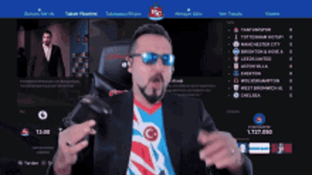 a man wearing sunglasses is sitting in front of a screen that says ' manchester city ' on it