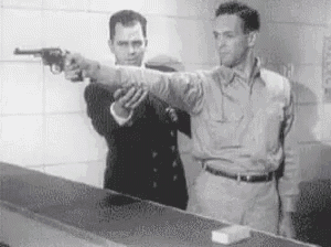 a man is pointing a gun at another man while another man watches .