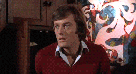 a man in a red sweater stands in front of a colorful wall