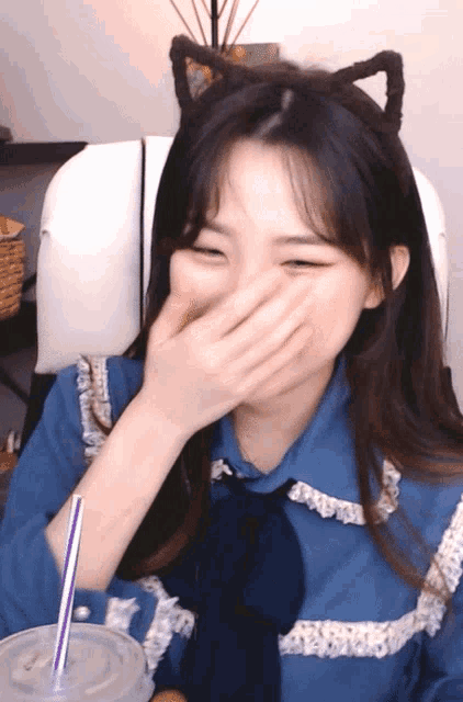 a girl wearing a cat ear headband covering her mouth